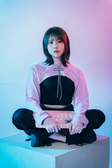 記事画像2: ピンクのゲームコントローラーを持つ若い女性