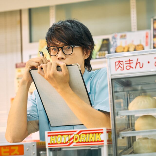 記事画像5: コンビニ店員が肉まんを手に持ち、伝票をチェックしている。