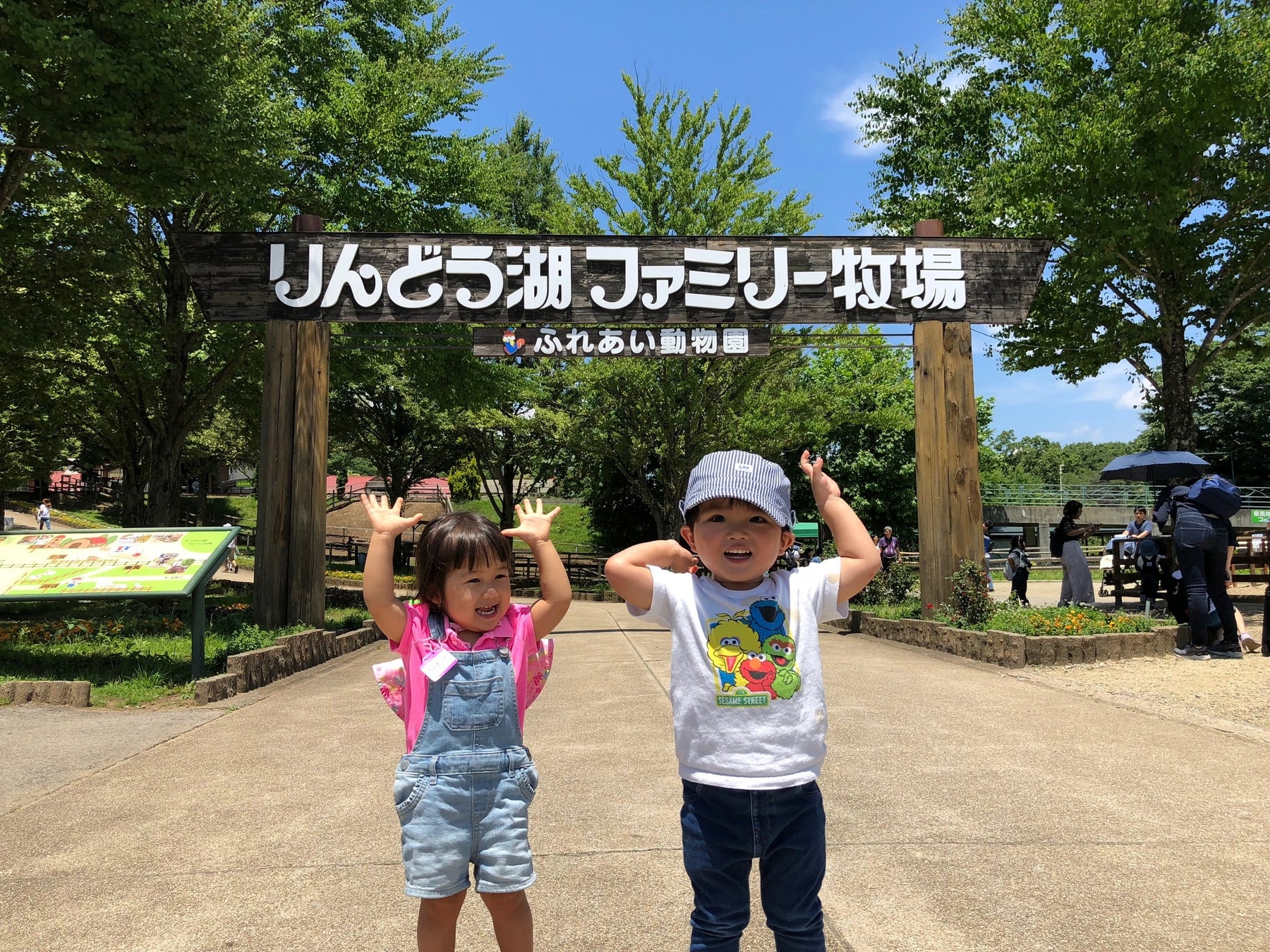 記事画像3: りんどう湖ファミリー牧場の入口で、2人の子供たちが楽しそうにポーズをとっている。