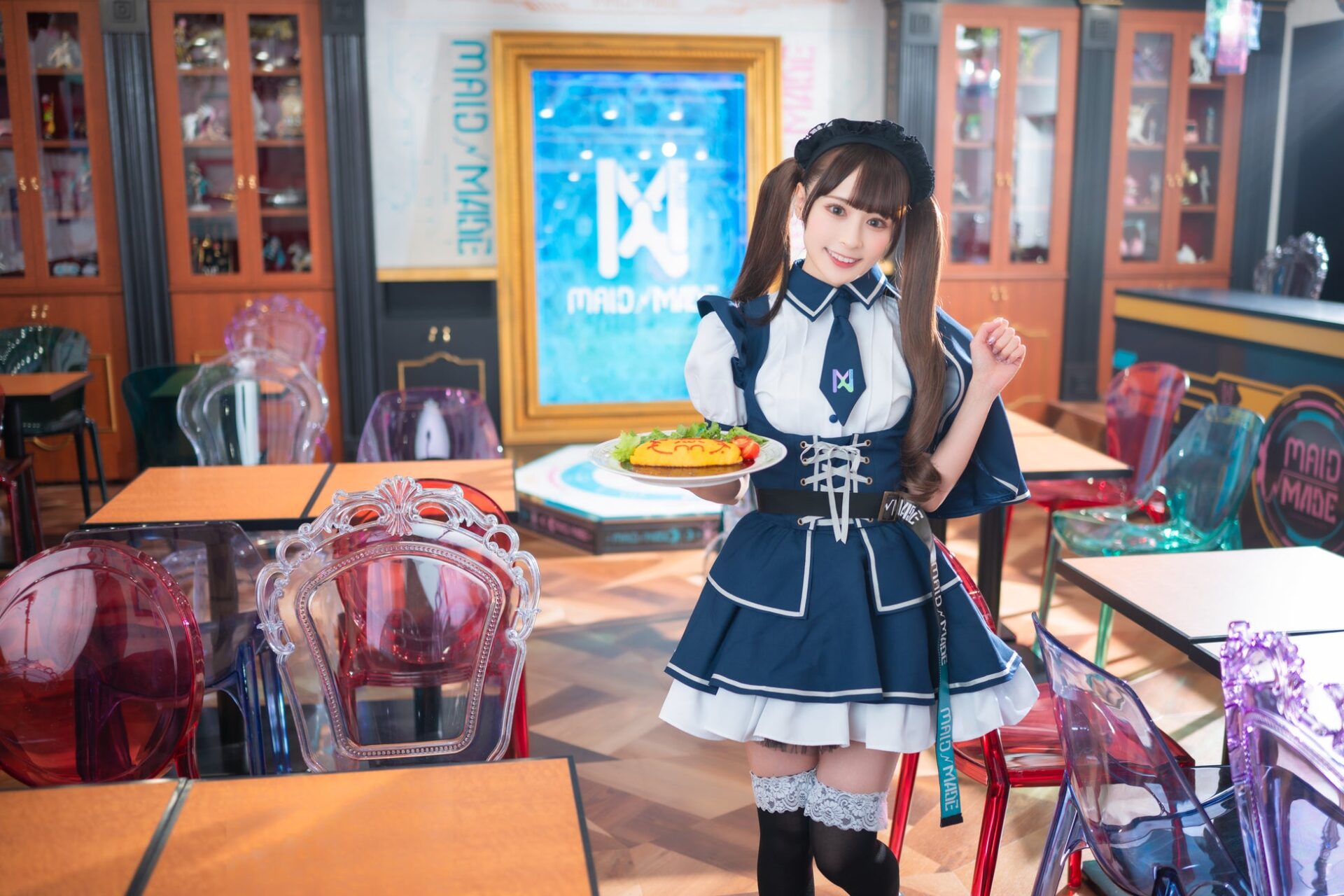 記事画像5: メイド服を着た女性がオムライスを運んでいる。店内にはカラフルな椅子が置かれている。