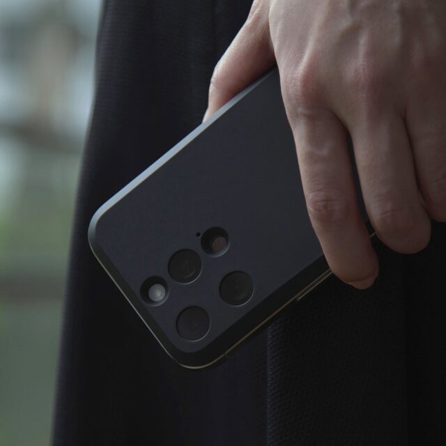 記事画像2: 黒いスマートフォンを手に持ち、カメラ部分をクローズアップ
