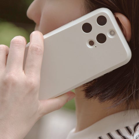 記事画像12: 白のスマートフォンを耳に当てて通話している様子