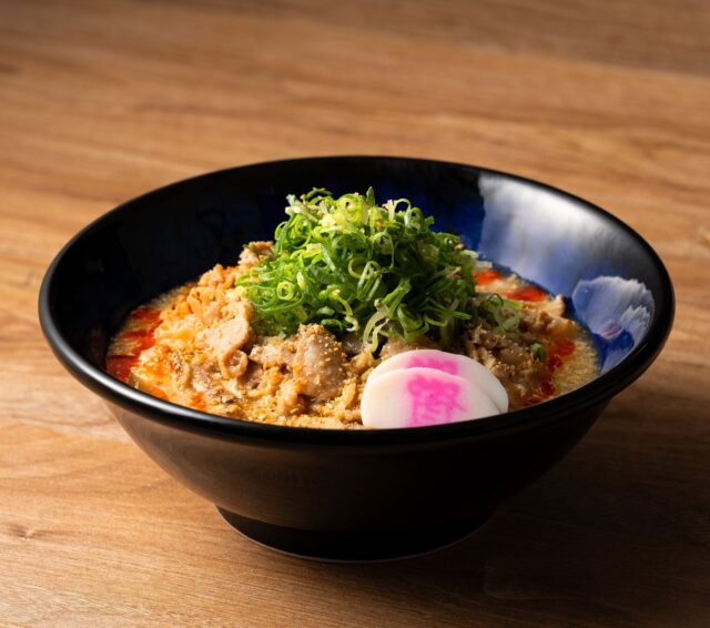 記事画像2: 黒い丼に入った、ネギとナルトが乗ったラーメン