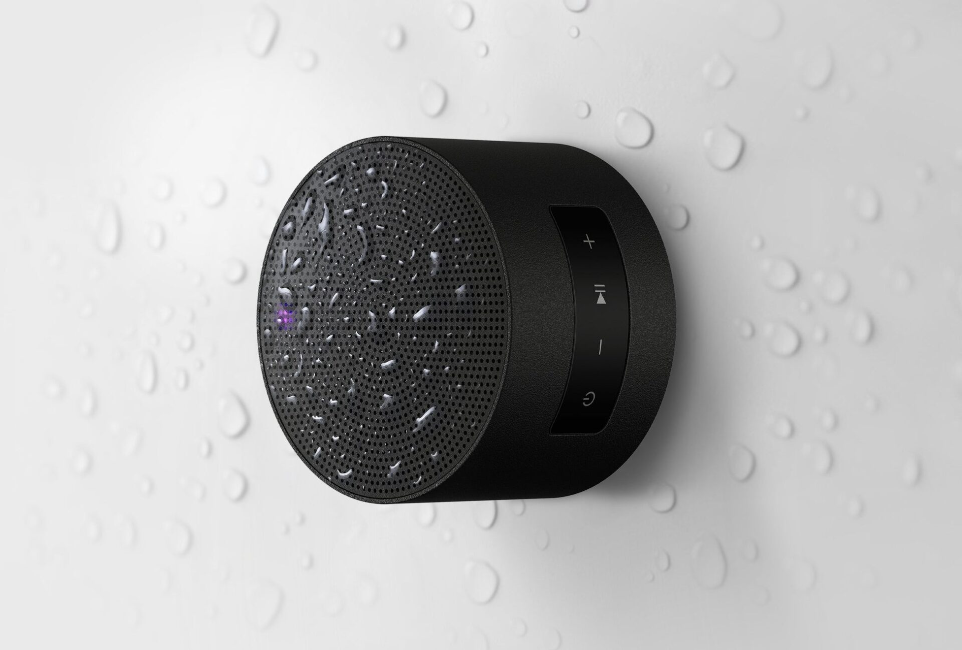 記事画像4: 水滴がついた防水Bluetoothスピーカー。黒い本体に再生/一時停止ボタンなどがある。