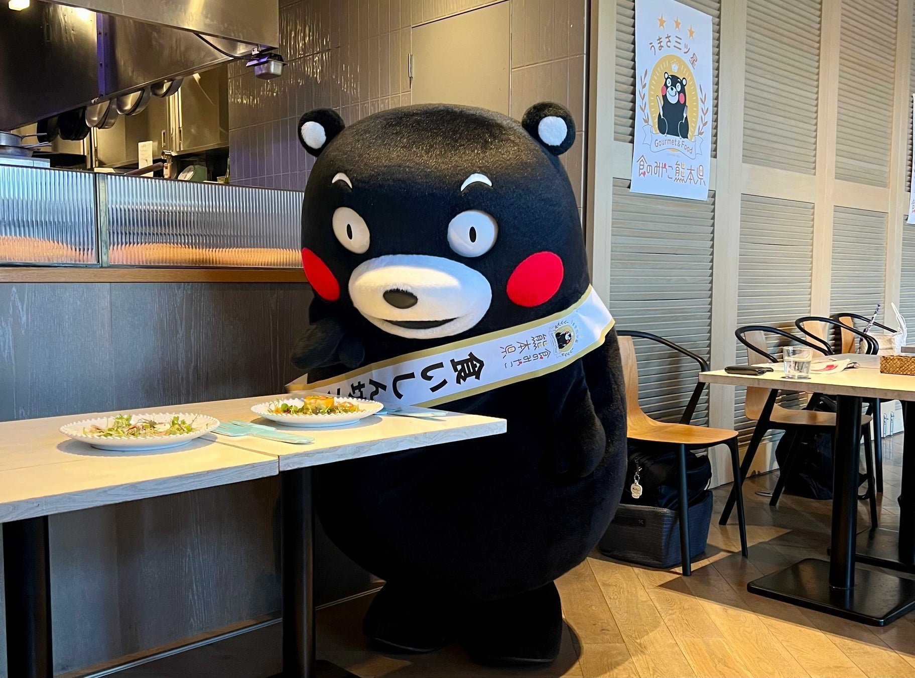 記事画像5: くまモンがテーブルに置かれた料理を前にしています。