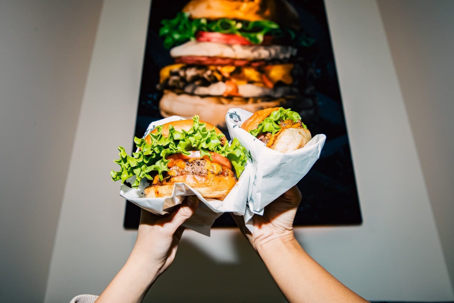 記事画像8: 2つの美味しそうなハンバーガーを両手で掲げる