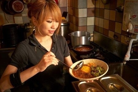 記事画像2: 女性がカレーを盛り付けている様子