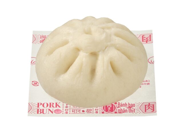記事画像2: 豚まんが紙の上に置かれており、様々な言語で「Pork Bun」と表記されています。