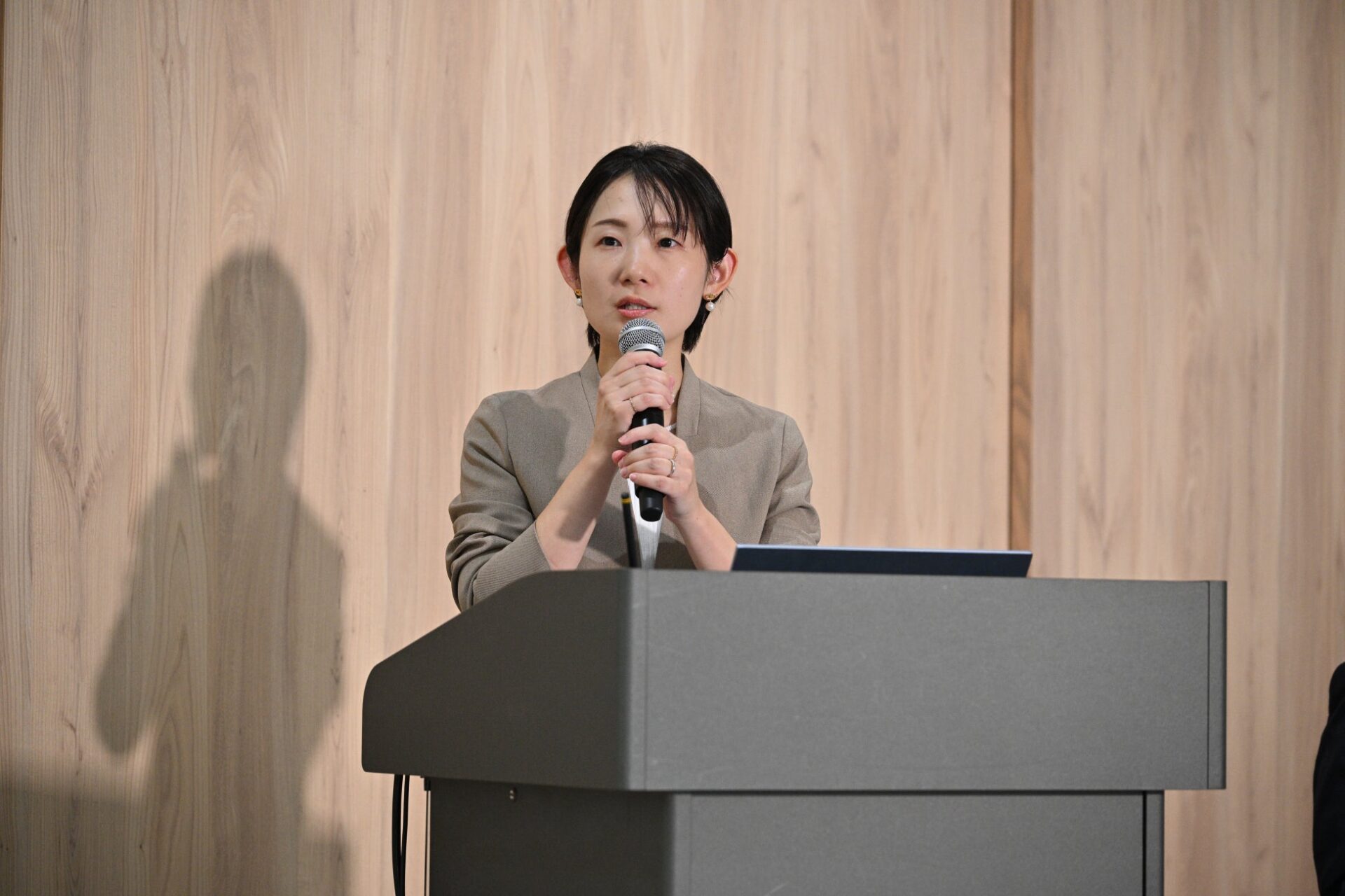 記事画像4: 壇上でマイクを持ち、講義をする女性