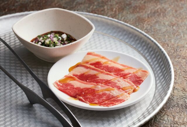 記事画像3: 焼肉用の牛肉が皿に並び、タレと薬味が入った小鉢が横に添えられています。