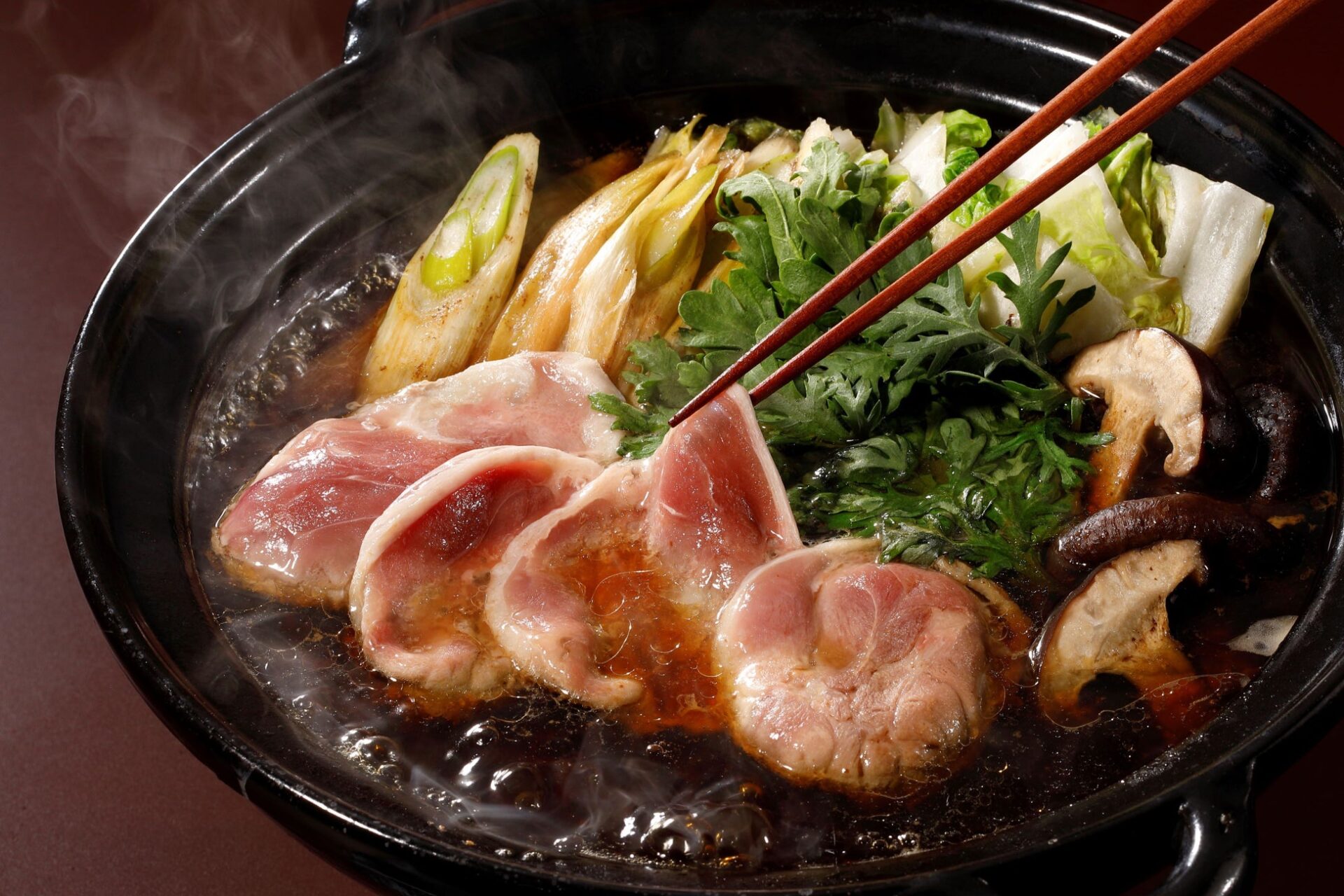 記事画像6: 鍋料理の具材に、割り箸で肉をつまんでいる様子