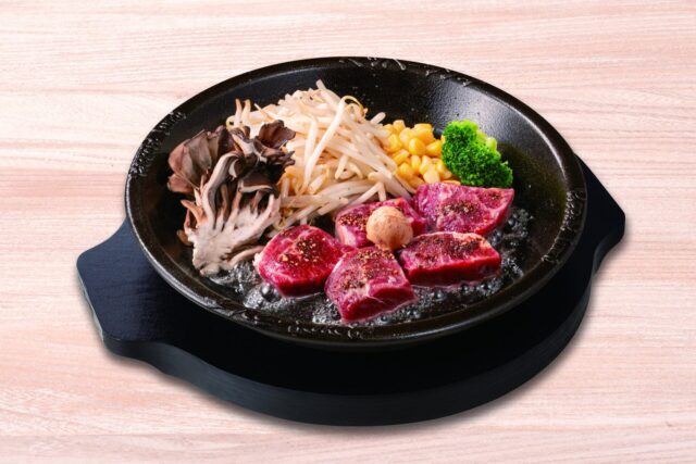 記事画像2: 鉄板の上で焼かれるステーキと野菜のグリル料理