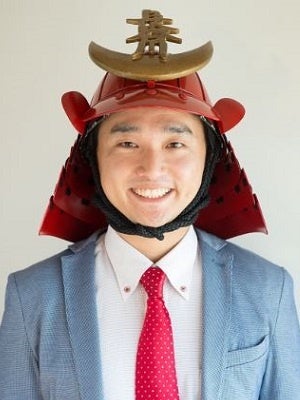 侍兜を被り、スーツ姿で笑顔の男性