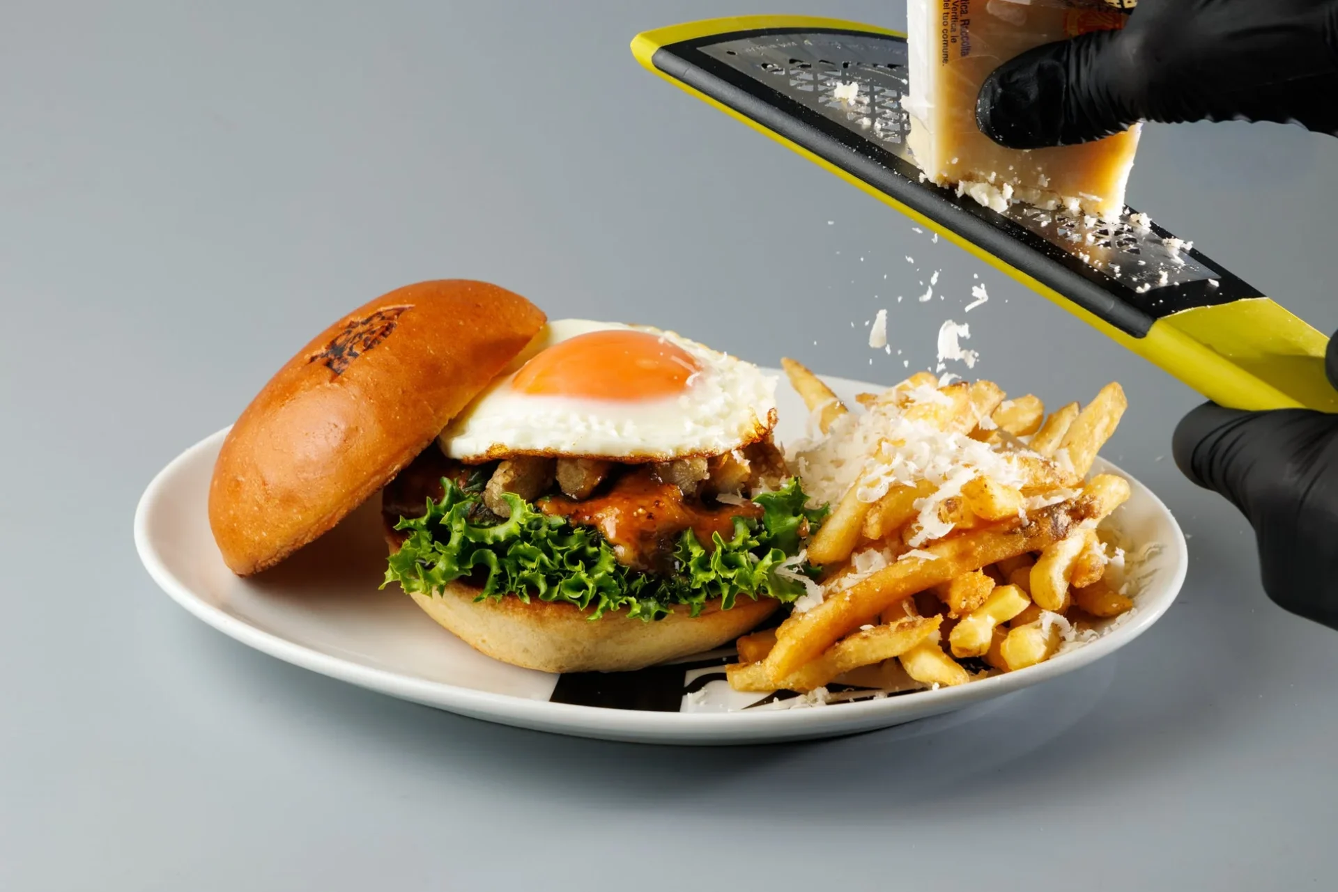 パルミジャーノ・レッジャーノを削りかけ中の月見バーガーとポテト