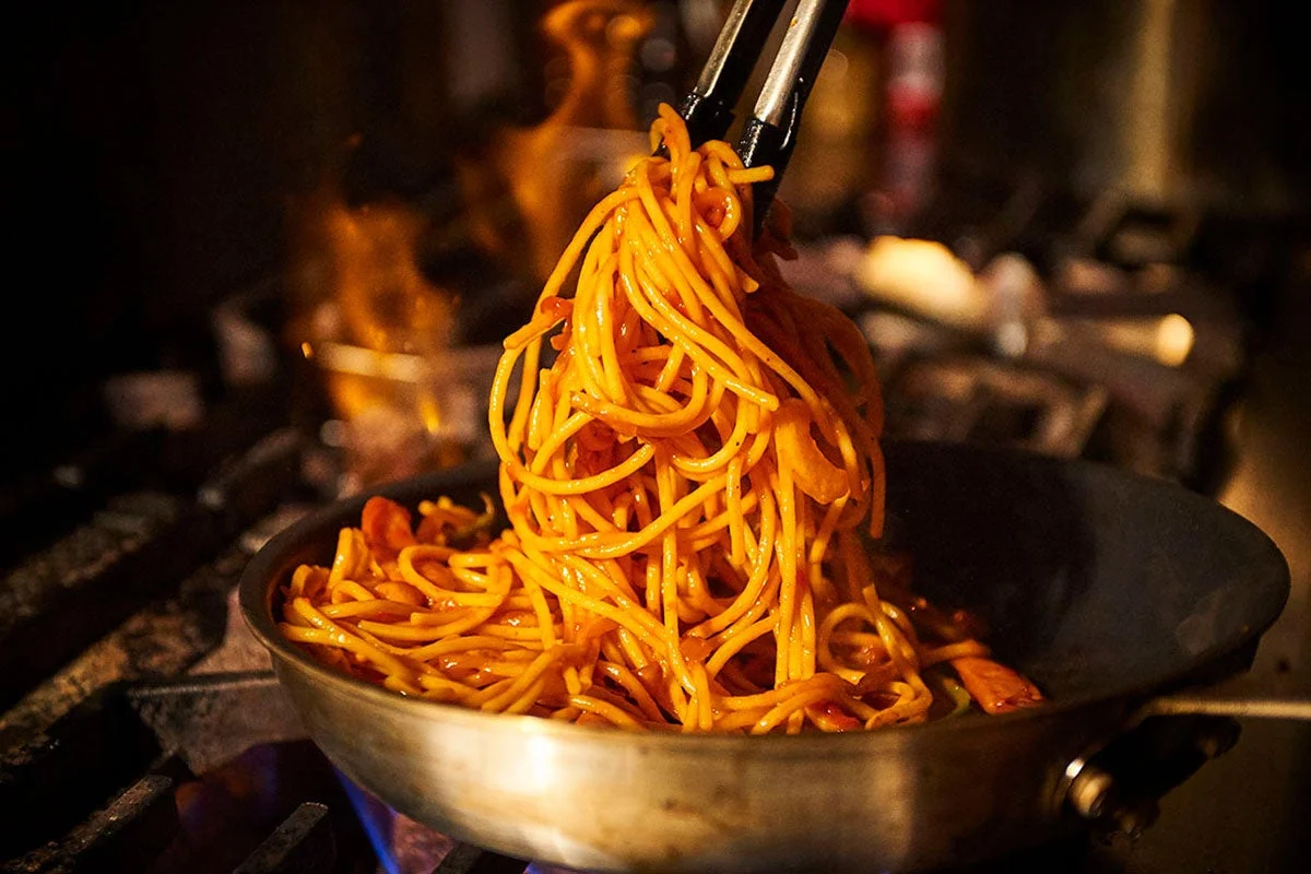 フライパンで極太麺のナポリタンを調理しているライブ感ある様子
