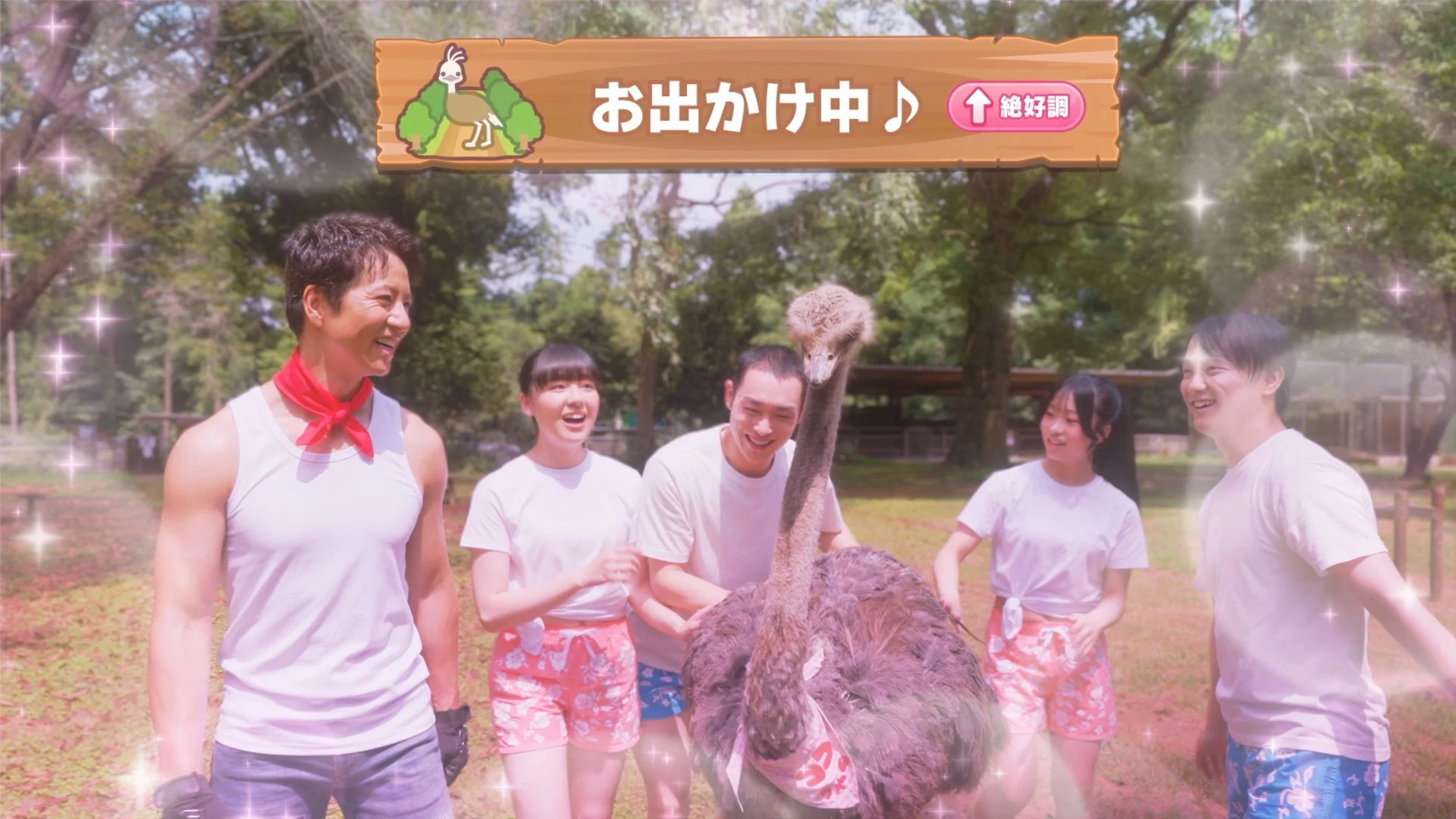 ケイン・コスギと仲間たちがダチョウを囲んで笑顔で触れ合う様子