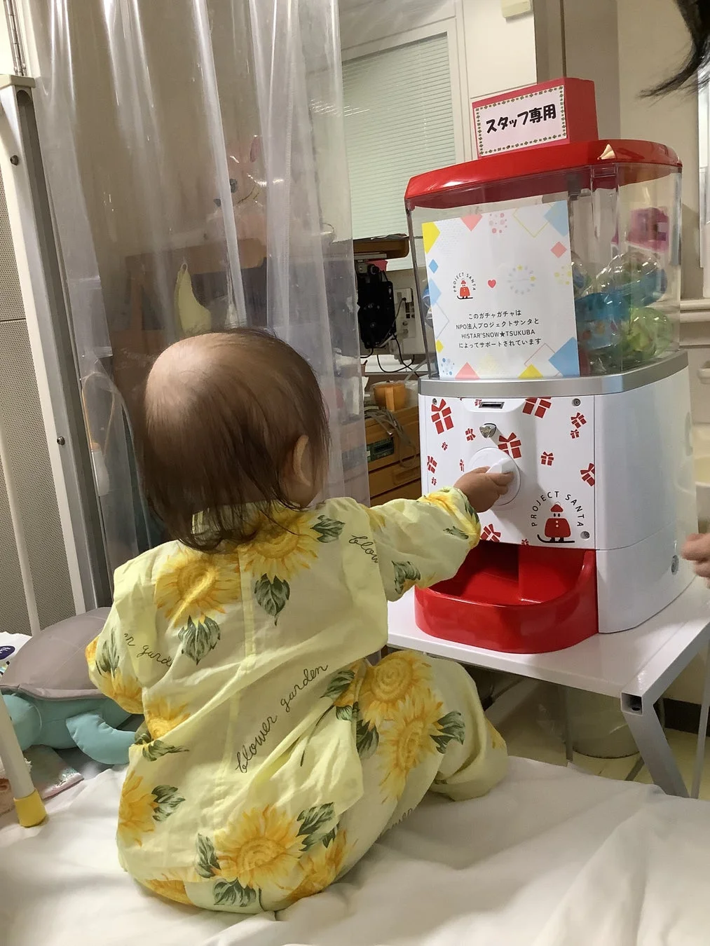 病院のベッドサイドでガチャガチャを回す子ども
