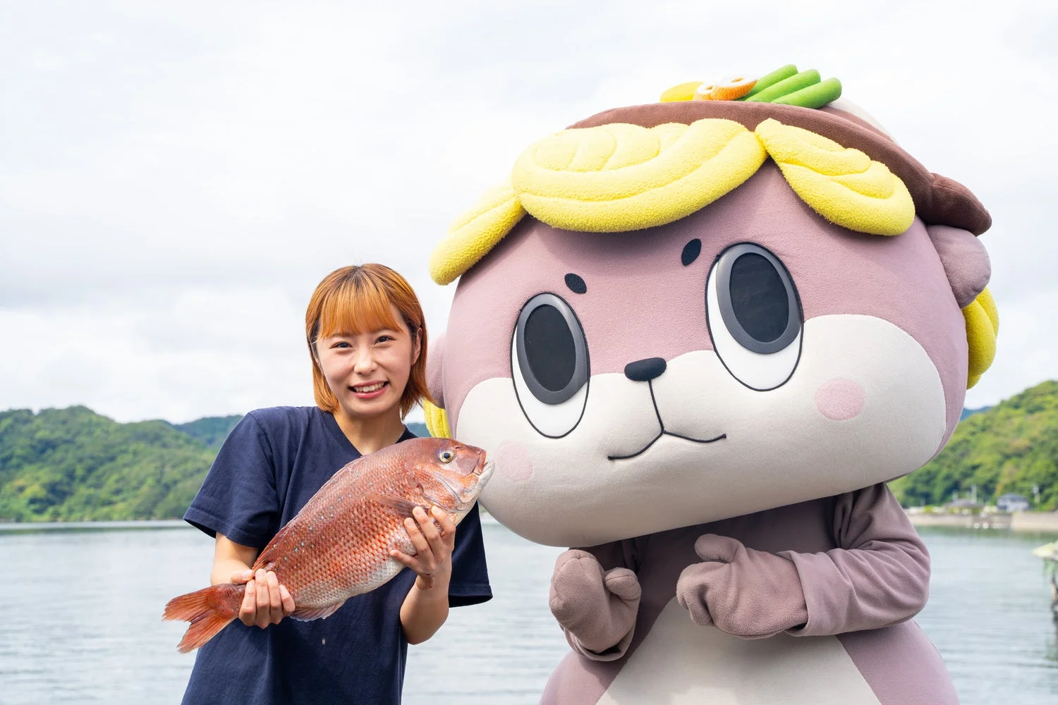 乙女鯛を抱える水産女子の小屋沙綾佳さんとご当地キャラクター「しんじょう君」