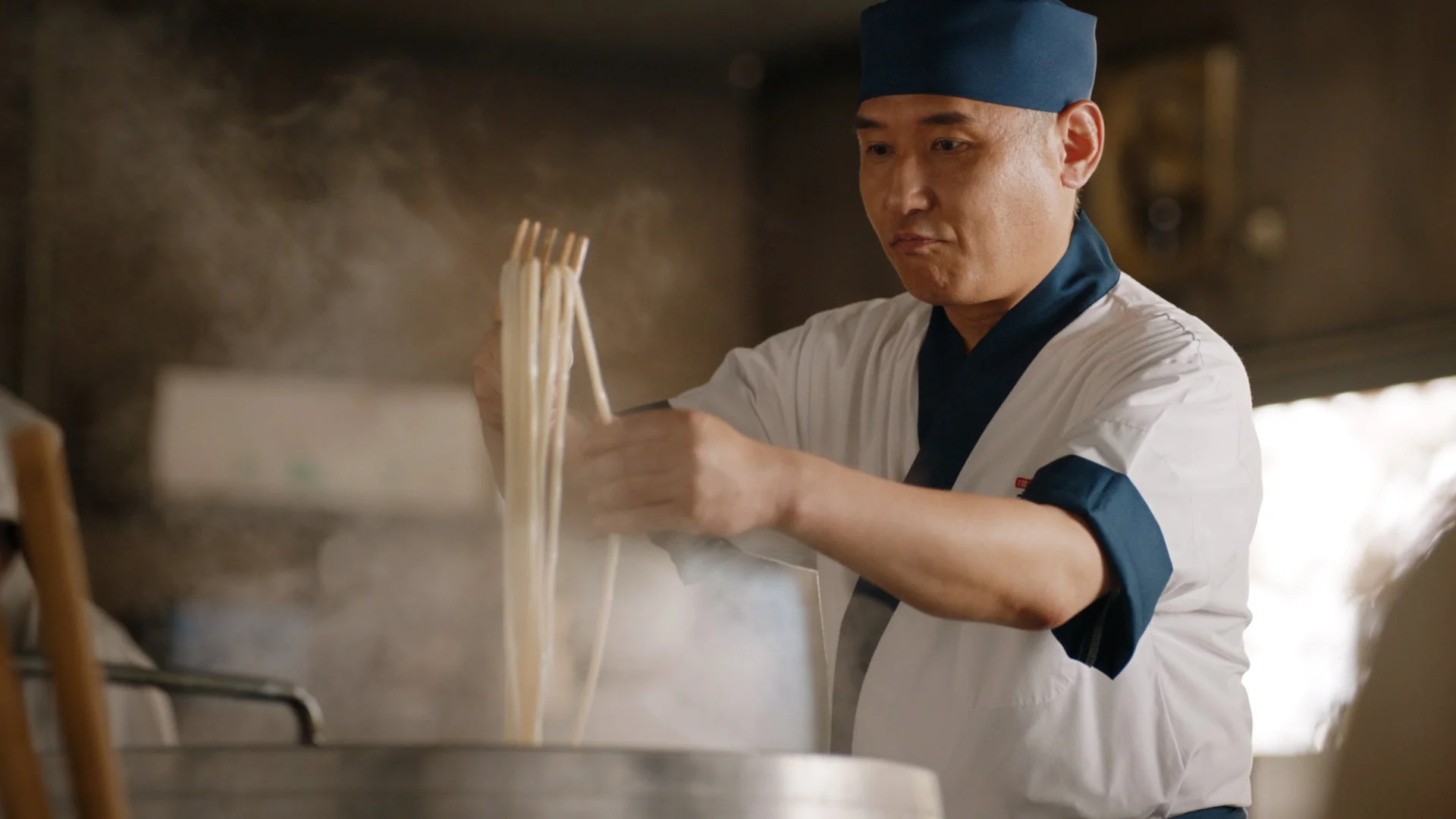 打ち立てのうどんを釜から上げる麺職人