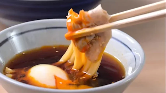 うどんを旨辛 豚つけ汁につけて食べる様子