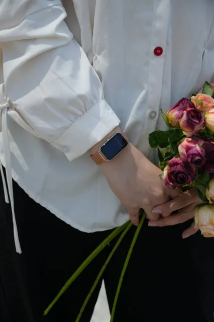 FOSMET FOS10スマートウォッチを腕に装着し、花束を持つ女性。