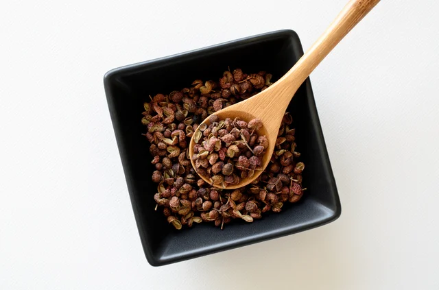 中華料理に使われる花椒の実と木製スプーン