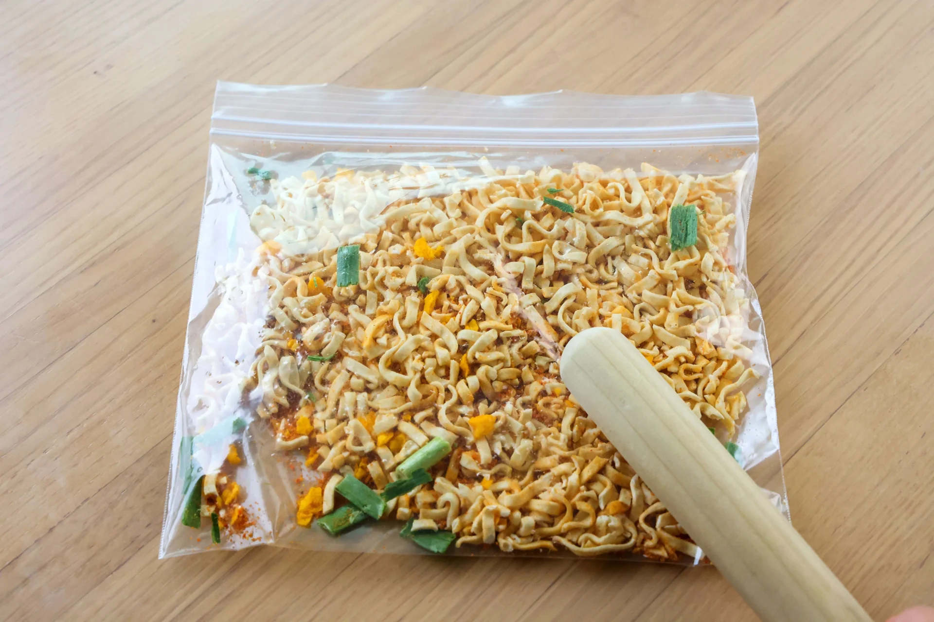ポリ袋に入れたカップ麺を麺棒で砕く様子