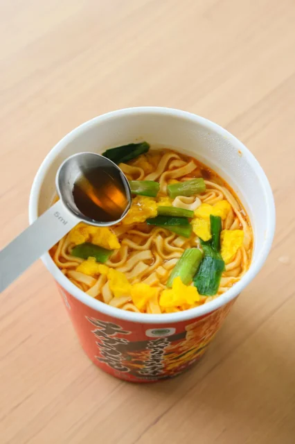 カップ麺にナンプラーを加えて混ぜる様子
