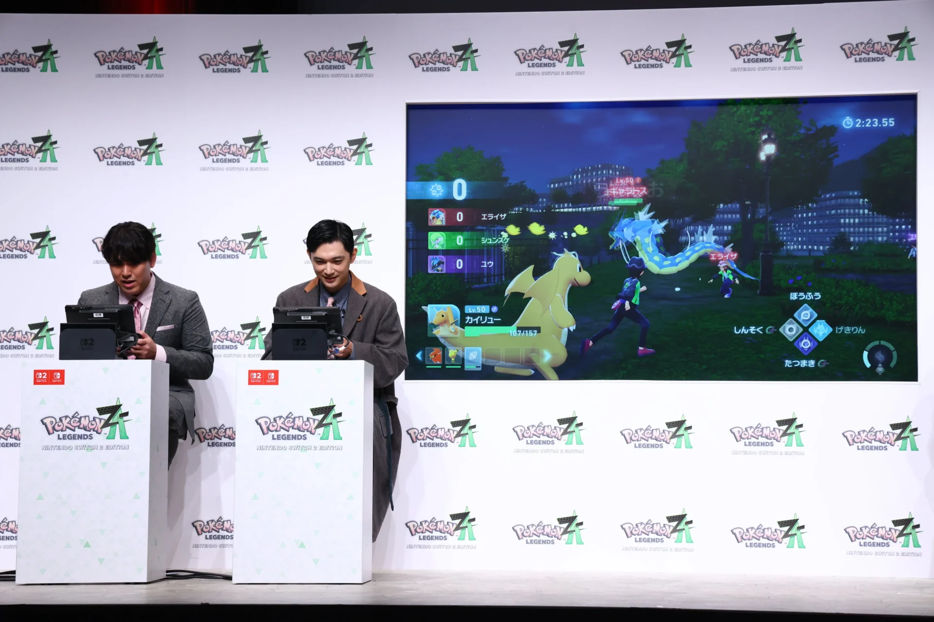 ゲームプレイ中の吉沢亮さんとオズワルド畠中さん、モニターにはバトルシーン
