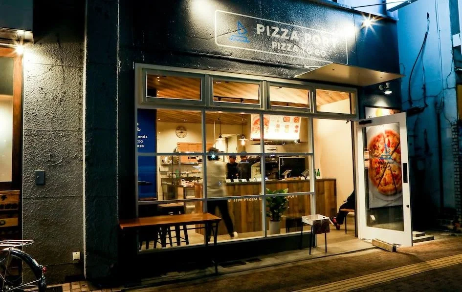 夜のPIZZA PORT店舗外観、店内が明るく見える
