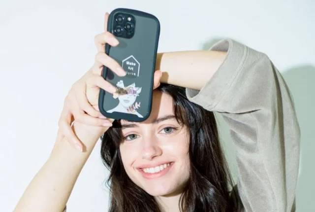 iPhone17対応のオリジナルスマホケースを掲げて微笑む女性