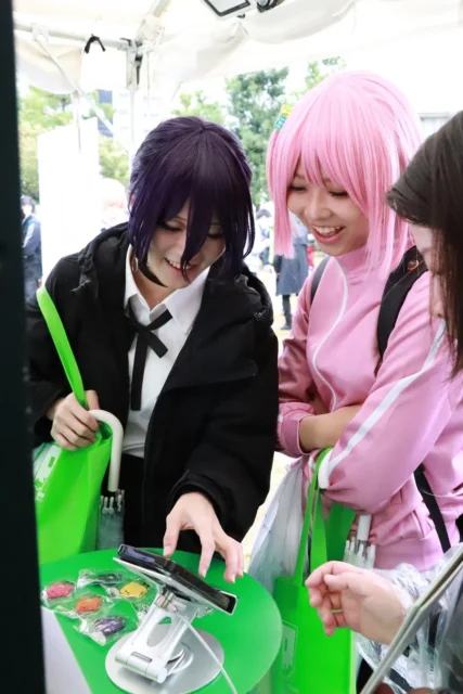 FLAIブースでAIチャット体験を楽しむ来場者のコスプレイヤー