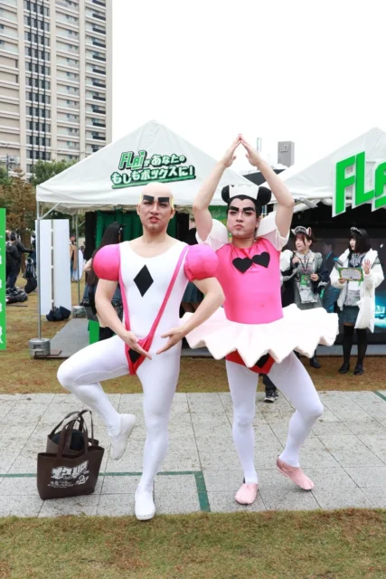 FLAIブース前でユニークなポーズを決める二人のコスプレイヤー
