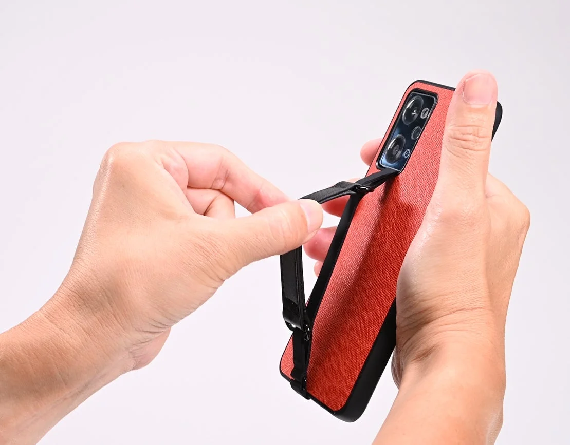 「ハンモッ君」を装着したスマホケースを指で引っ張り、もちもちフィット感を表現している様子