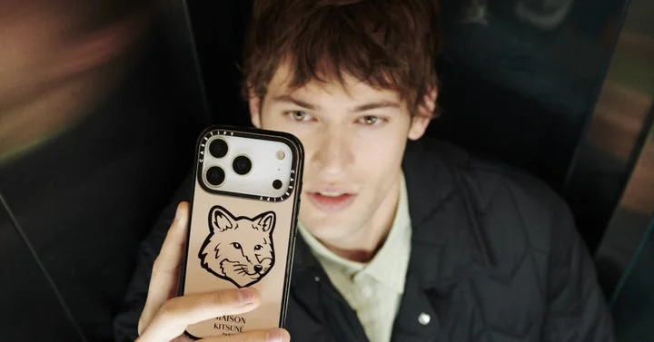 Maison Kitsuné x CASETiFYコラボのベージュ系キツネロゴスマホケースを持つ男性