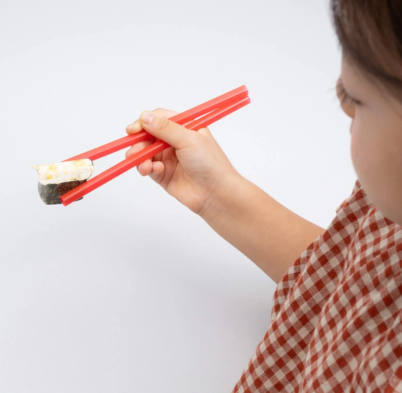 子どもがくら寿司コラボ付録の回転寿司ゲームで箸を使い寿司をつかみ取る様子