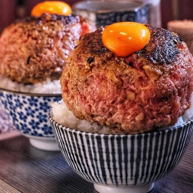 ご飯の上に盛られた焼きたてハンバーグと卵黄