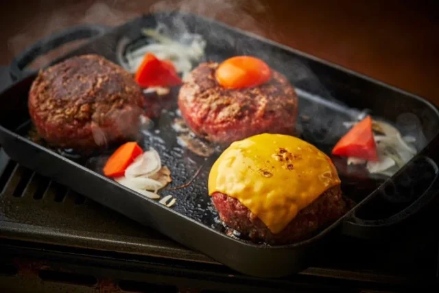 鉄板で焼かれるチーズと卵黄が乗ったハンバーグ