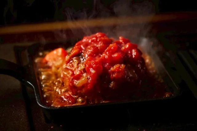 鉄板で焼かれるトマトソースがけハンバーグ
