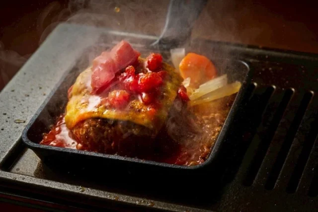 鉄板で焼かれるチーズとトマトソースのハンバーグ
