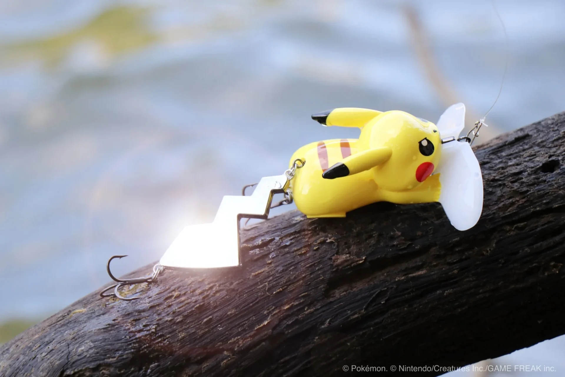 水辺の流木に置かれたピカチュウ アイアンテールver.ルアー。