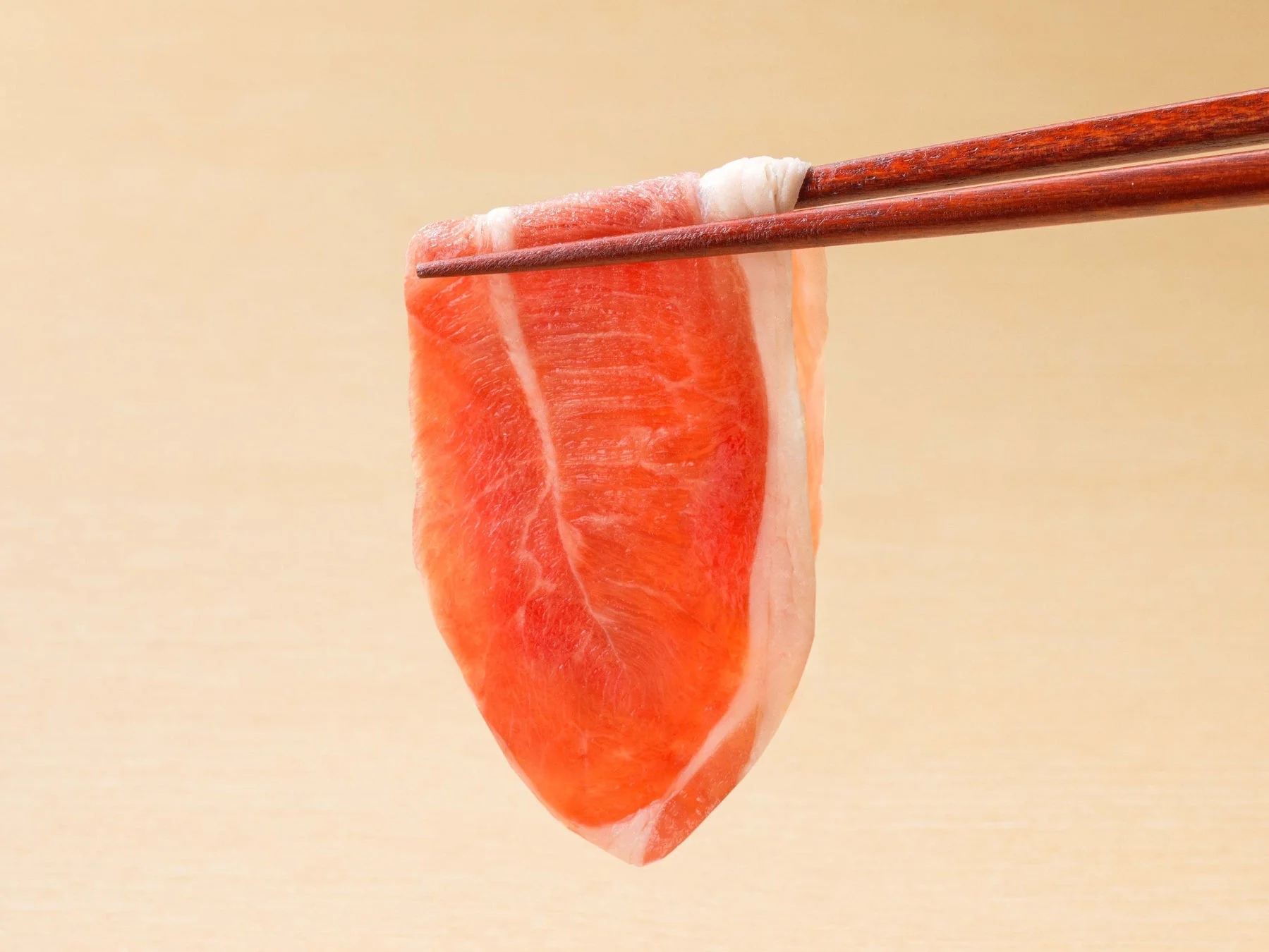 箸で持ち上げられた新鮮な薄切りラム肉