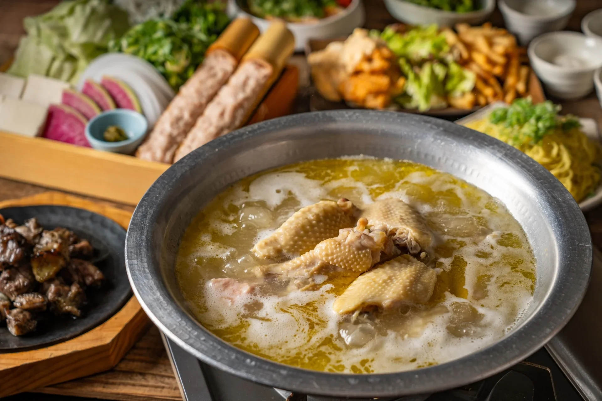 塚田農場 水炊き堪能コースの全景。地鶏の水炊き鍋を中心に、地鶏炭火焼、チキン南蛮などの料理が並ぶ。