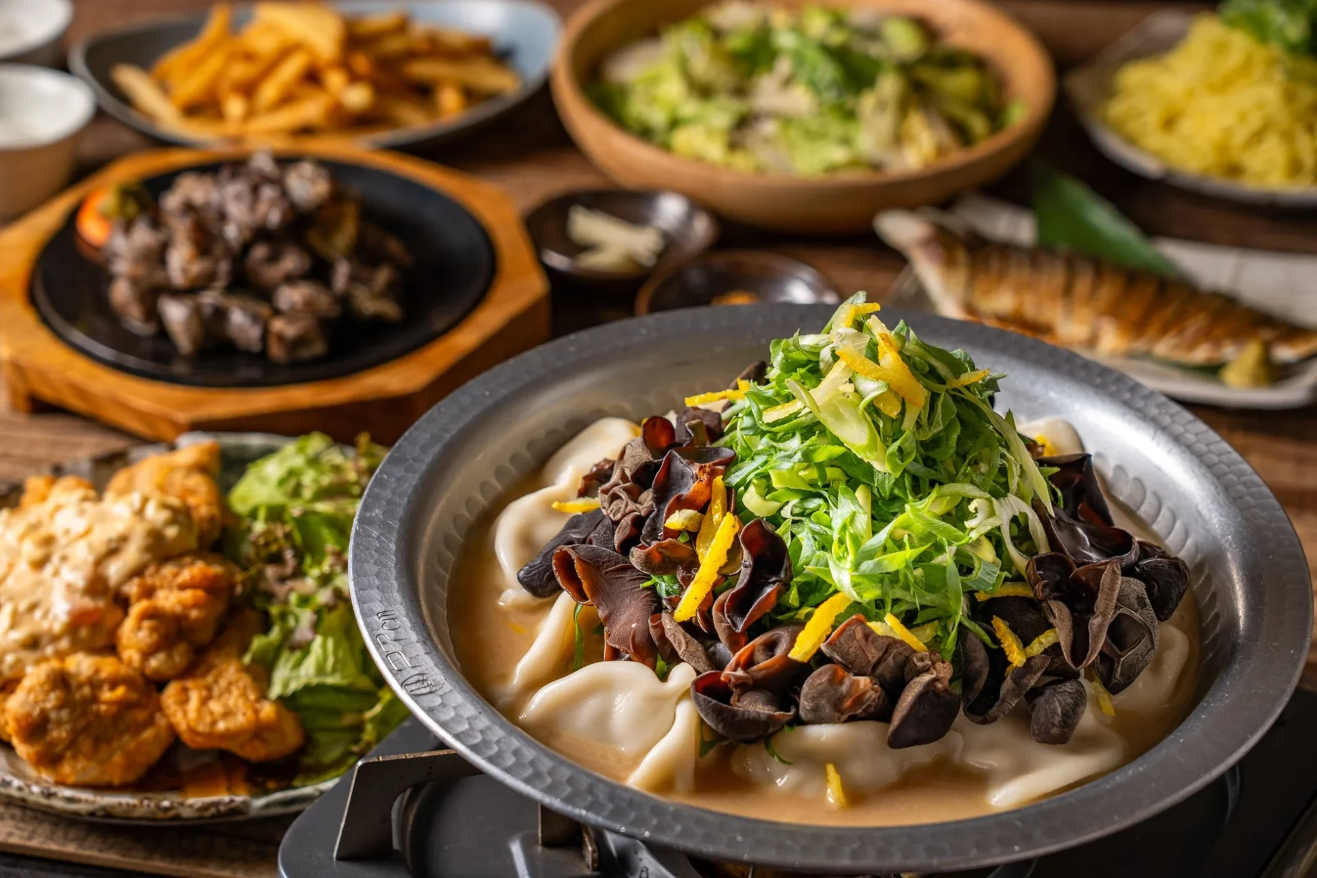 炊き餃子コースの全景。九条ネギとキクラゲがたっぷりの炊き餃子を中心に、地鶏炭火焼、チキン南蛮などが並ぶ。