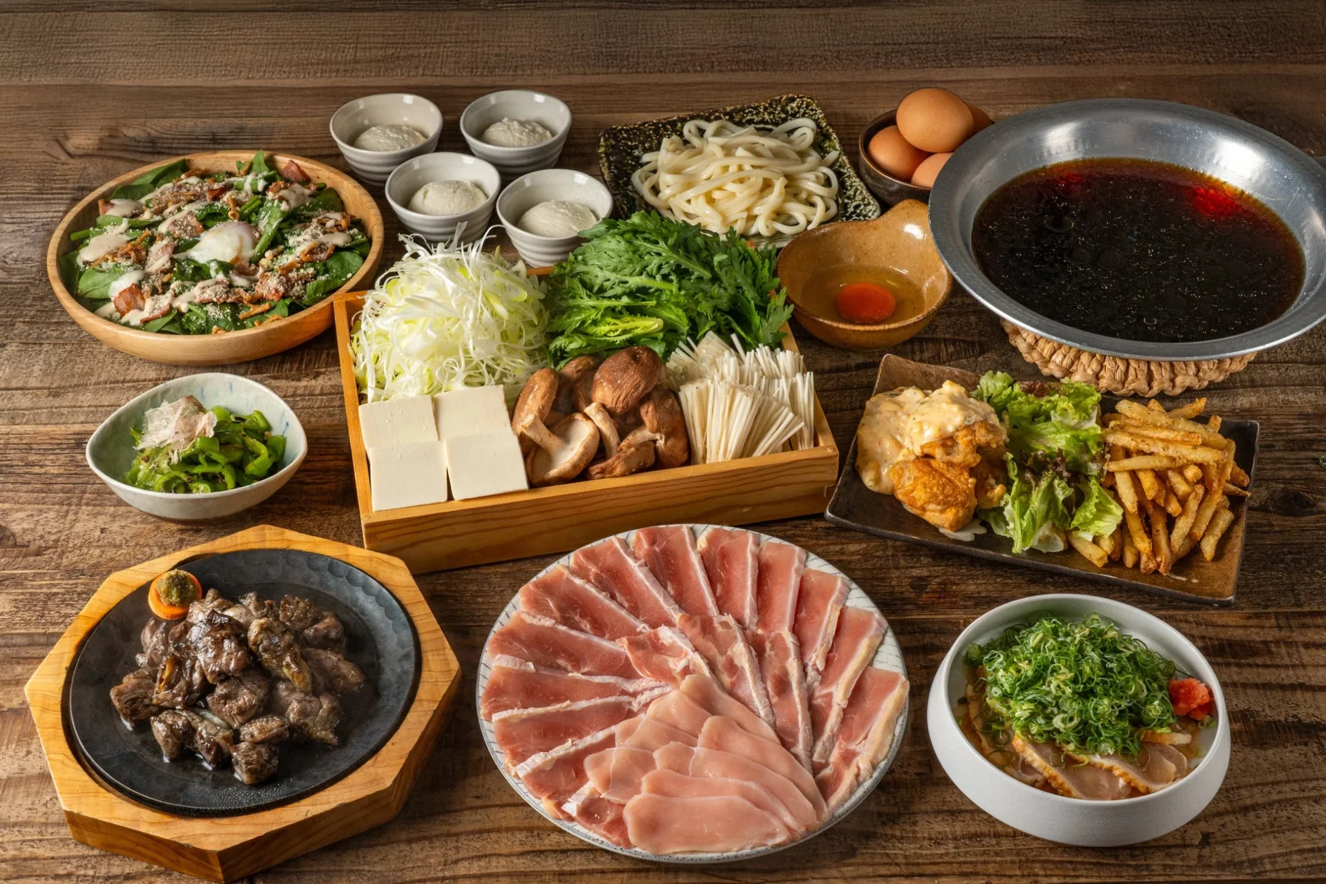 地鶏のしゃぶすきコースの全景。地鶏の薄切り肉と野菜、地鶏炭火焼、チキン南蛮などが並ぶ。