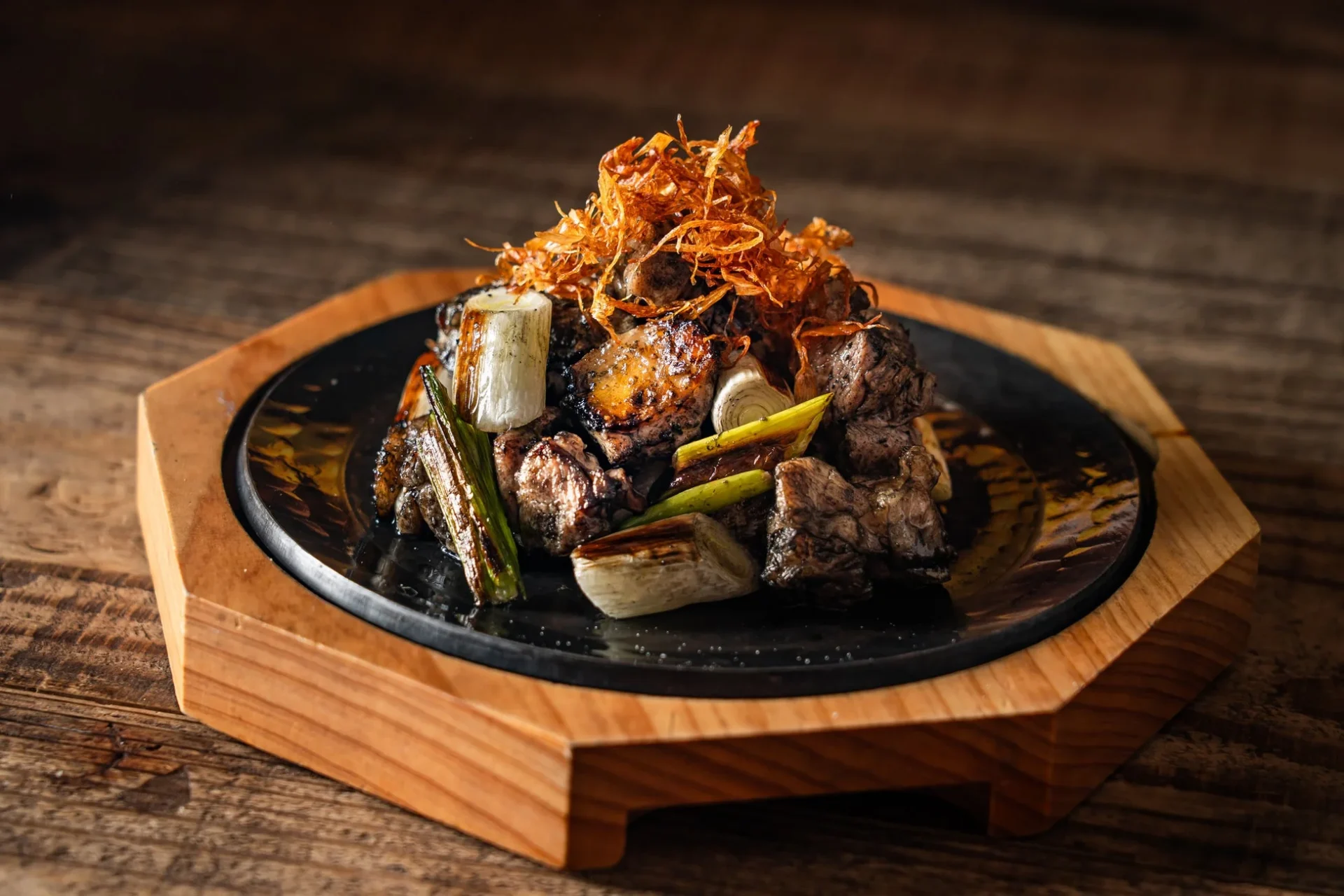 冬の地鶏炭火焼～とろシャキ塩ねぎま～。香ばしく焼かれた地鶏と栗原ねぎが鉄板に盛り付けられている。