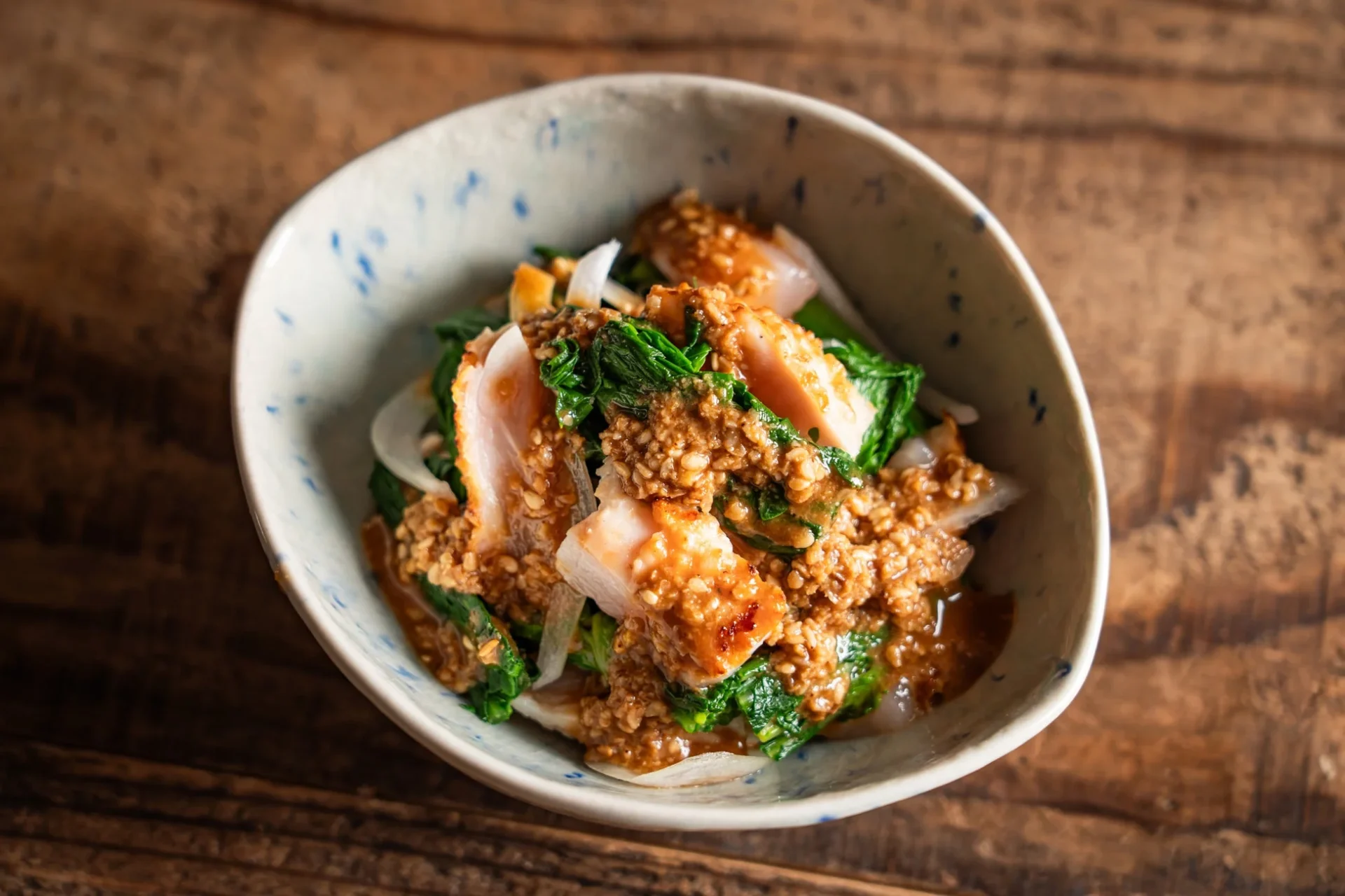 地鶏たたきと大葉春菊の胡麻和え。地鶏のたたきと大葉春菊が特製胡麻ダレで和えられている。