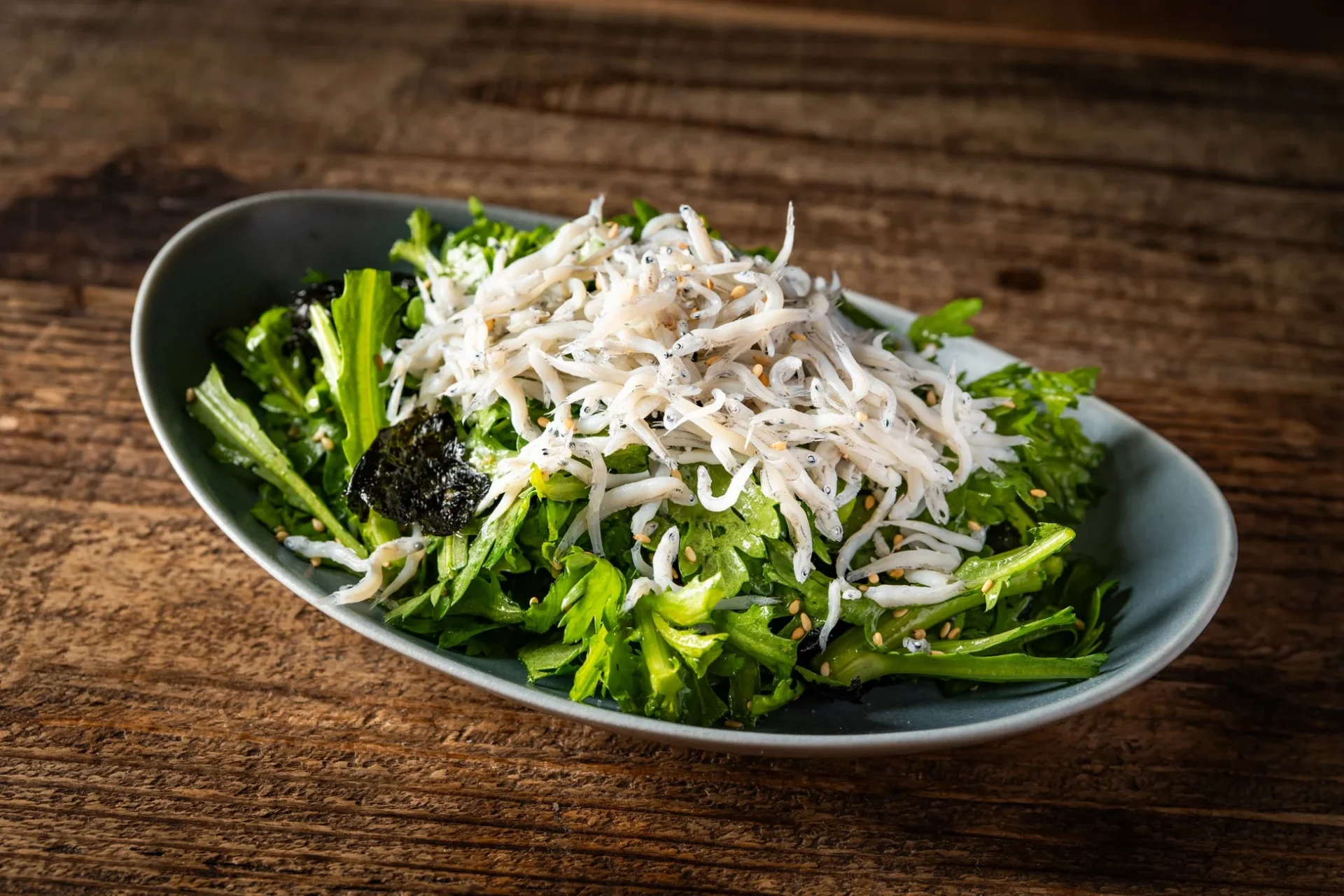 大葉春菊としらすのチョレギサラダ。新鮮な大葉春菊の上にたっぷりのしらすが盛り付けられている。
