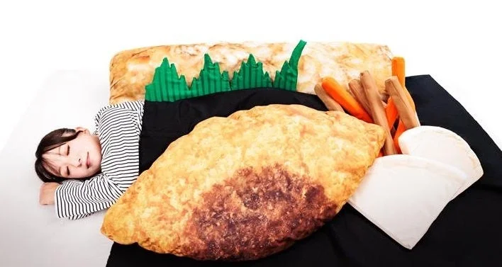 ほっともっとの白身フライとちくわ天の巨大クッションを抱いて寝ている子供のイメージ。