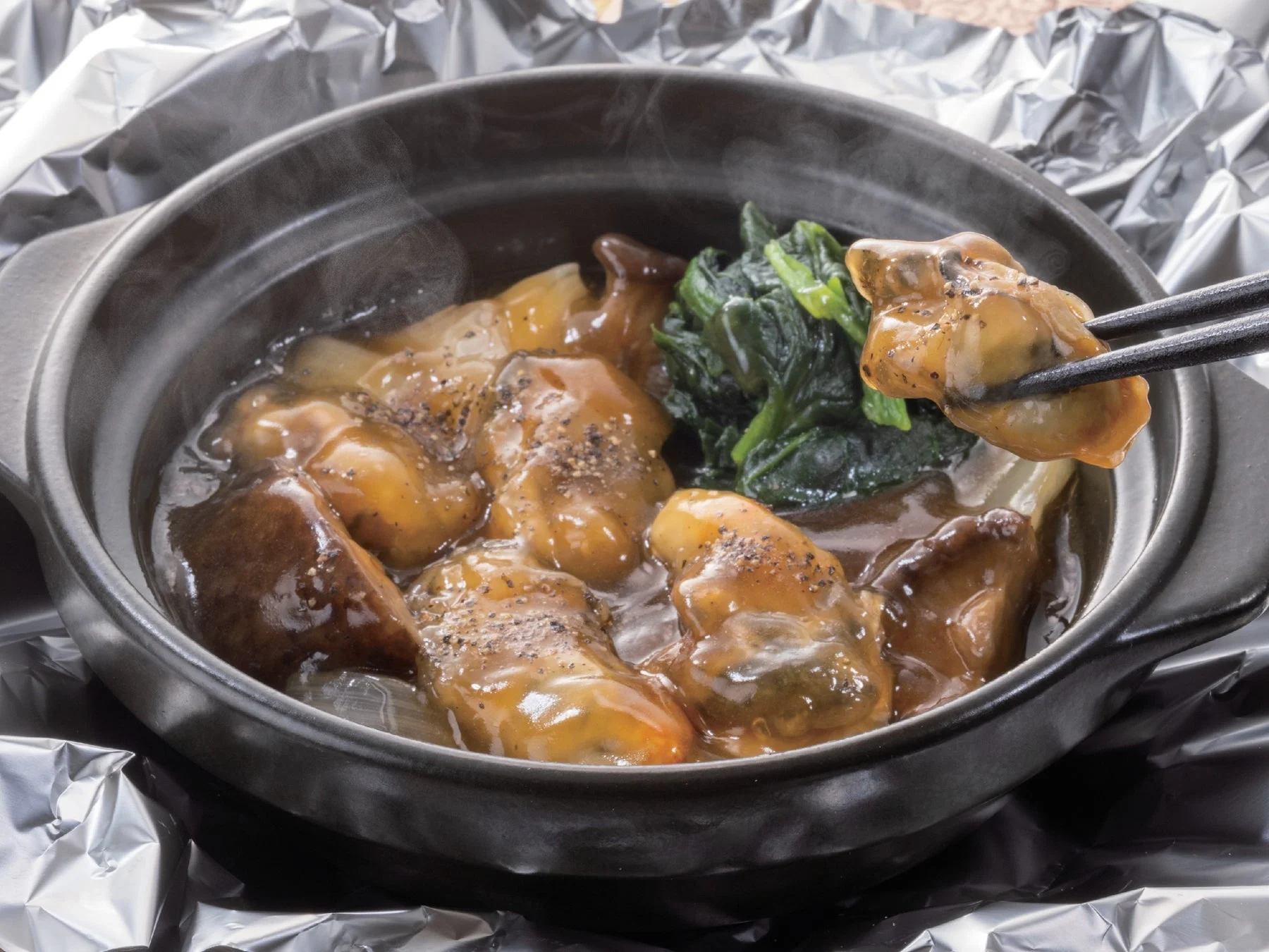 ホイルに包まれオイスターベースの餡で煮込まれた牡蠣の土鍋焼き